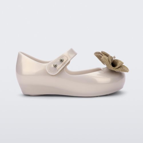 Side view of a beige Ultragirl Sweet baby ballerina flat with bow