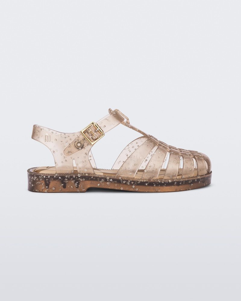 Side view of a clear beige Possession kids sandal with star glitter