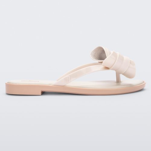 Side view of a Melissa slim strap flip flop in light beige with bow applique