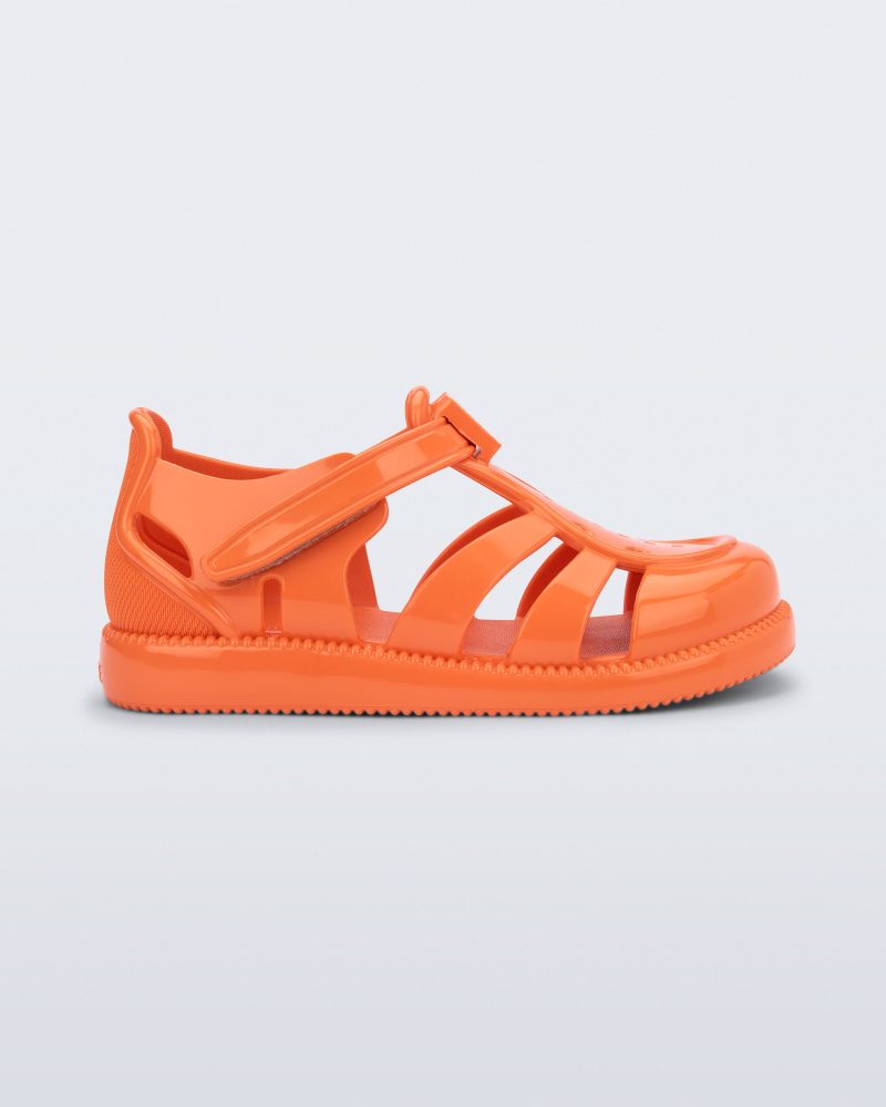 Side view of an orange baby Hip Daydream sandal