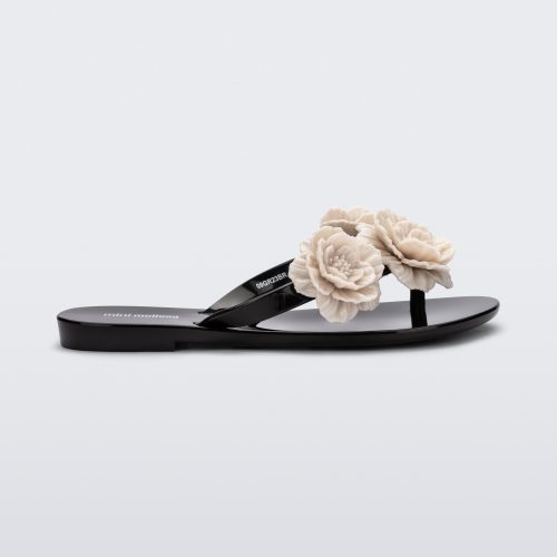 Side view of a black Harmonic Springtime kids flip flop with three beige flowers.