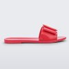 An outter side view of a red Melissa Babe slide with a buckle like bow detail on the front strap.