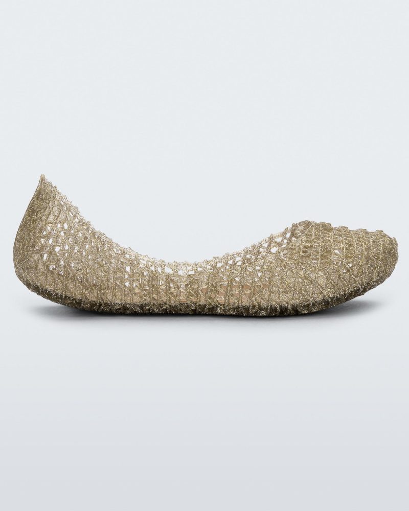 An outter side view of a gold glitter Mini Melissa Campana flat with a woven detail base.