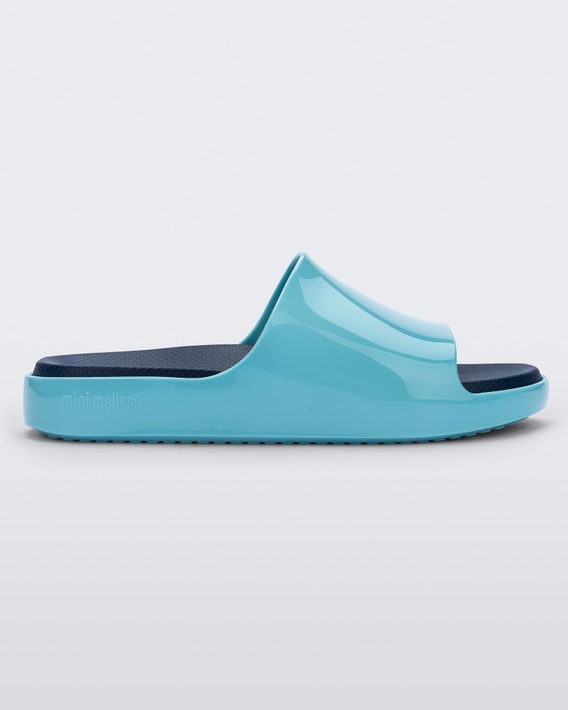 Side view of a blue Mini Melissa Cloud slide with a navy blue insole and a lighter blue base.