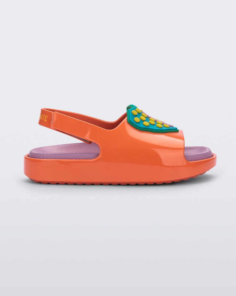 Side view of a orange/pink Mini Melissa Cloud sandal with a velcro back strap, pink insole, orange base and a blue/yellow heart drawn on the front.