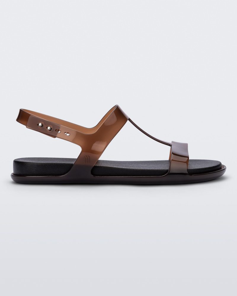 Side view of a clear brown / black Melissa Adore sandal with two translucent brown straps, joined together by a third strap and a black insole.