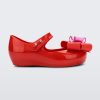 Side view of a red Mini Melissa Ultragirl Sweet flat with a top strap and a pink and red bow detail on the toe.