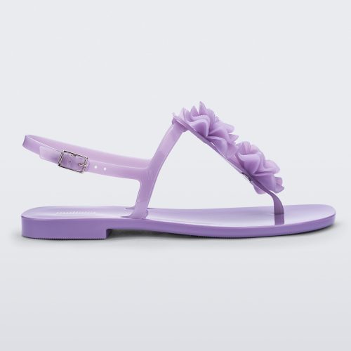 Side view of a lilac Melissa Harmonic Squared Garden sandal with a flower decoration on the front strap.