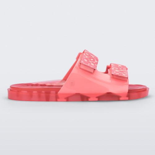 Side view of a pink Melissa Brave Wide slide with a pink base, pink and yellow floral print velcro straps and a translucent pink insole.