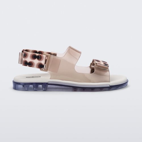 An inner side view of a clear brown Melissa Brave Papete sandals with a white insole, brown circle print, transparent beige straps and a velcro back.