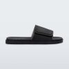 Side view of a black Melissa Brave Slide with a black velcro top strap and black insole.