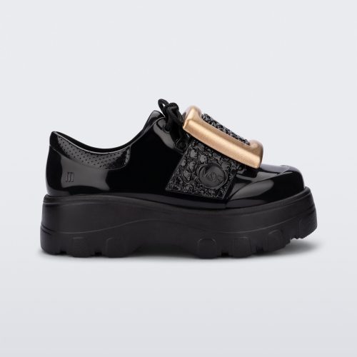 Side view of a black Melissa Buckle Up Kick Off platform sneaker with a gold buckle.