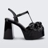 Side view of a black Melissa Tie Party Heel with several straps and a bow on the toe.