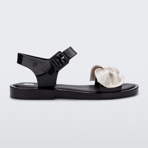 Side view of a Melissa Tie Mar sandal in black with buckle ankle strap and beige 3D bow detail on front straps