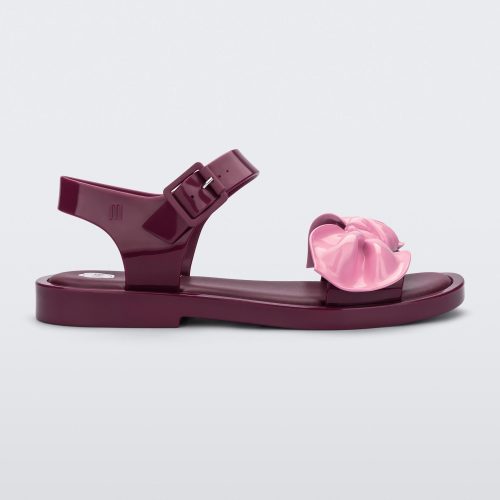 Side view of a red/pink Melissa Tie Mar Sandal with a red base, an ankle strap and a front strap with a pink bow on the front.