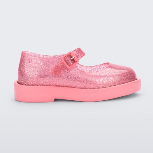 Side view of a transparent glitter pink Mini Melissa Lola loafer with a rounded toe and a pink strap and buckle.