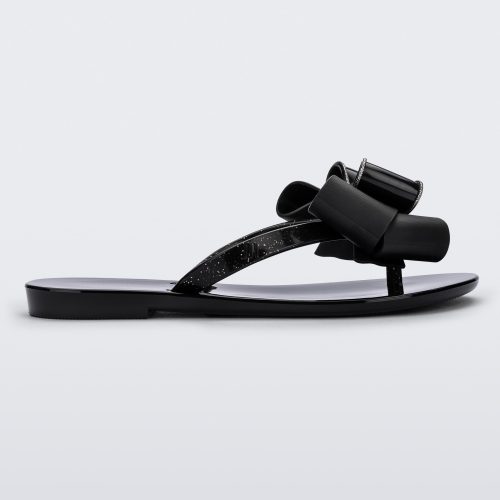 Side view of a black Mini Melissa Harmonic Sweet flip flop with a glitter and black bow detail on the straps.