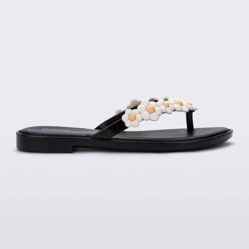 Side view of a black Melissa Spring Flip Flop with white and yellow flowers on them.