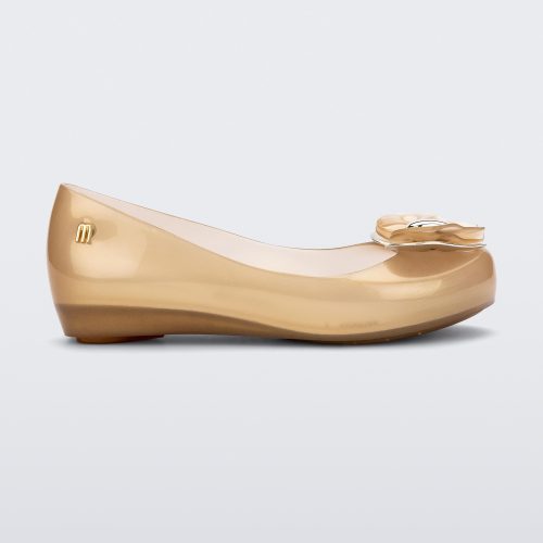 Side view of a Pearly Beige Mini Melissa Ultragirl flat with a heart buckle bow detail on the toe.