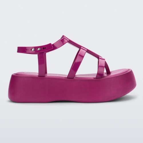 Side view of a pink Melissa Caribe High Platform sandal with two pink front straps joined by a vertical strap intersecting the ankle strap and a black sole.