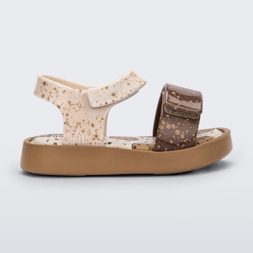 Side view of a beige/brown Mini Melissa Jump Candy sandal with white and brown crumb detail straps and a print of cookies on the insole.