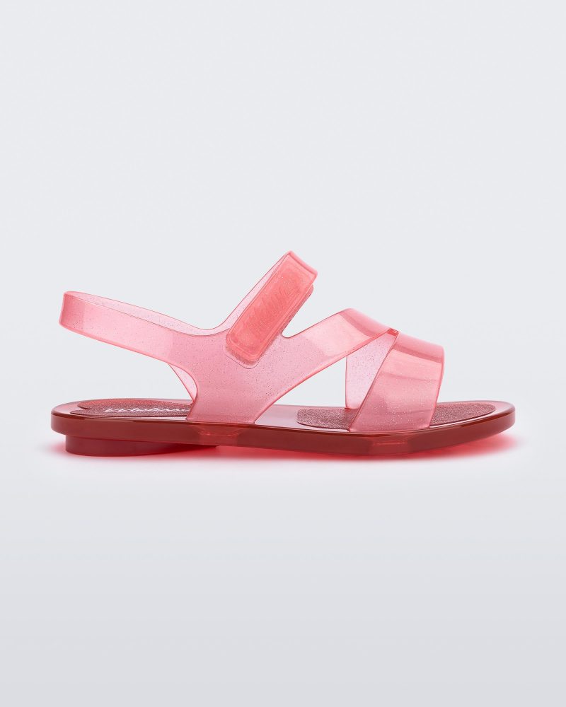 Side view of a pink/red Mini Melissa The Real Jelly Paris sandal with three front straps and a back ankle strap.