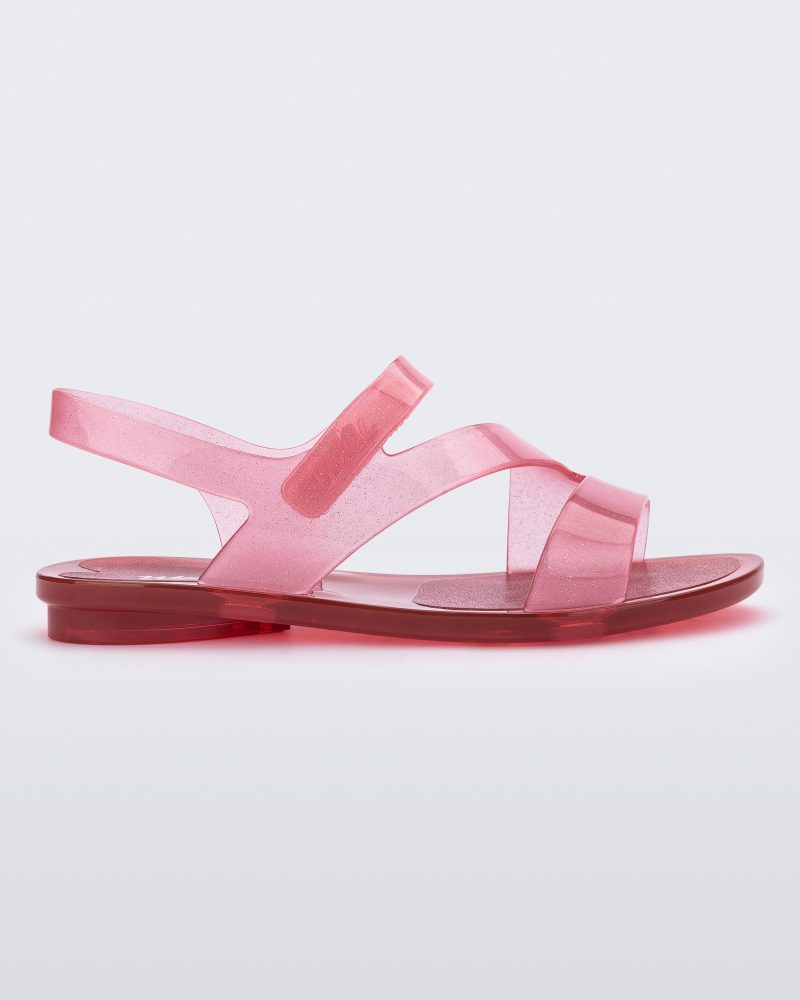 Side view of a pink/red Mini Melissa The Real Jelly Paris sandal with three front straps and an ankle strap with a clear pink/red glitter base.