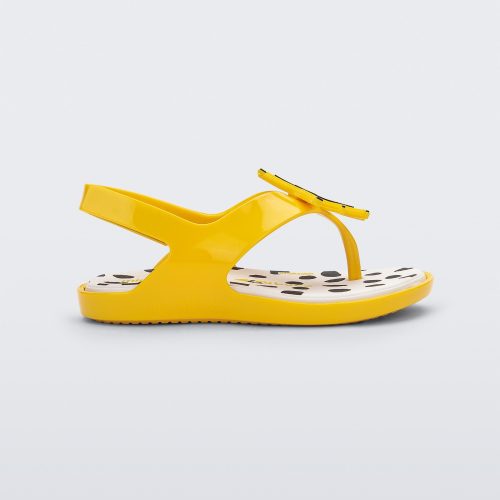 Side view of a yellow Mini Melissa Sunny sandal with a black base, a banana drawing on top of the straps and a black and white polka dot insole.