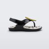 Side view of a black Mini Melissa Sunny sandal with a black base, a banana drawing on top of the straps and a black and white polka dot insole.