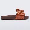 Side view of a Melissa Tie Beach slide with brown sole and brown/orange strap with 3D bow detail.