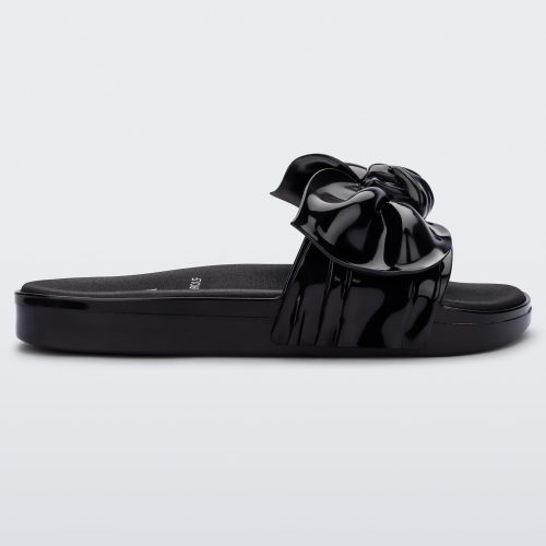 Side view of a black Melissa Tie Beach slide with a black base and a bow on the front strap.