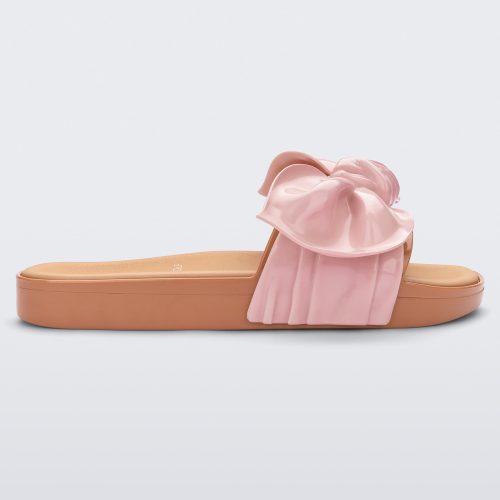 Side view of a beige/pink Melissa Tie Beach slide with a beige base and a pink bow on the top strap.