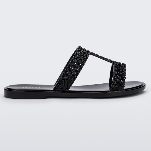 Side view of a black Melissa Glowing slide with black gem stones on the straps and a black sole.