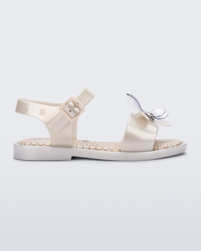 Side view of a metallic white Mini Melissa Mar Bugs sandal with a metallic white base, an ankle strap, front strap with a bug detail buckle on the front and a honey comb pattern sole.