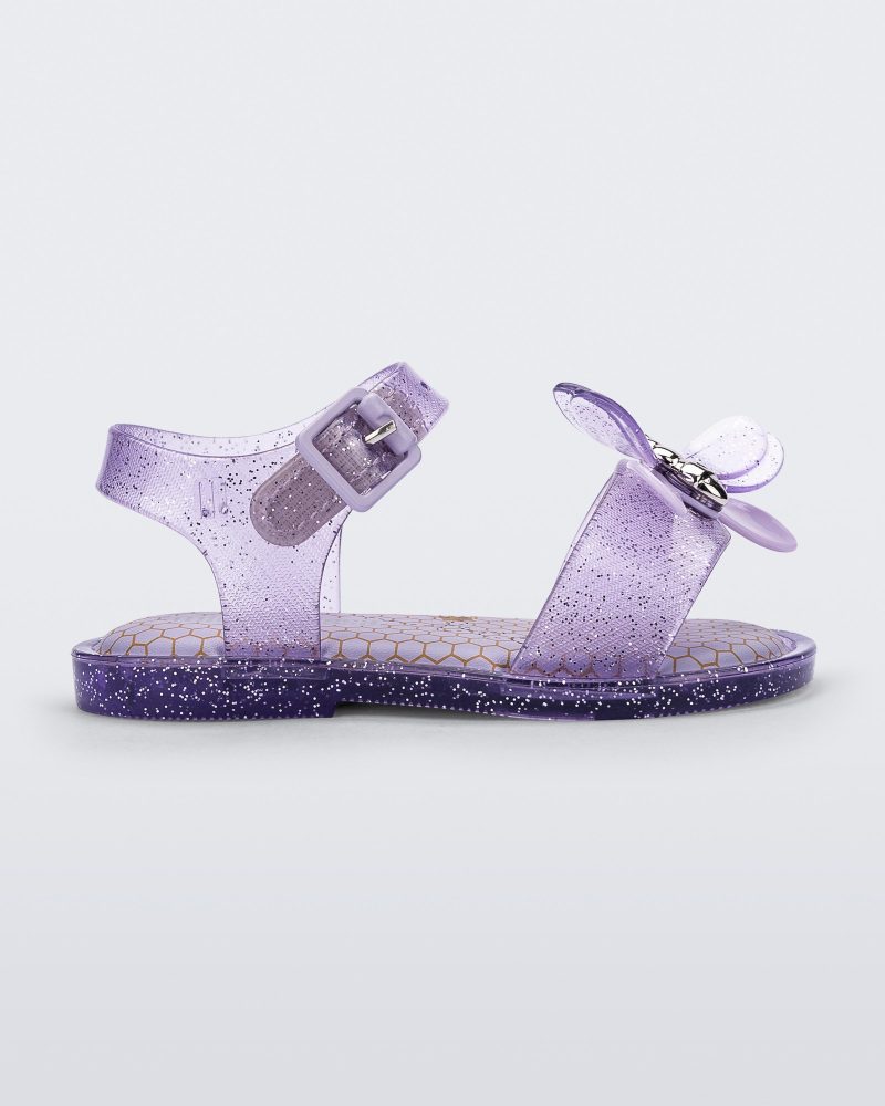 Side view of a lilac glitter Mini Melissa Mar Bugs sandal with a honeycomb pattern insole and a lilac bug detail with a silver buckle on the front.