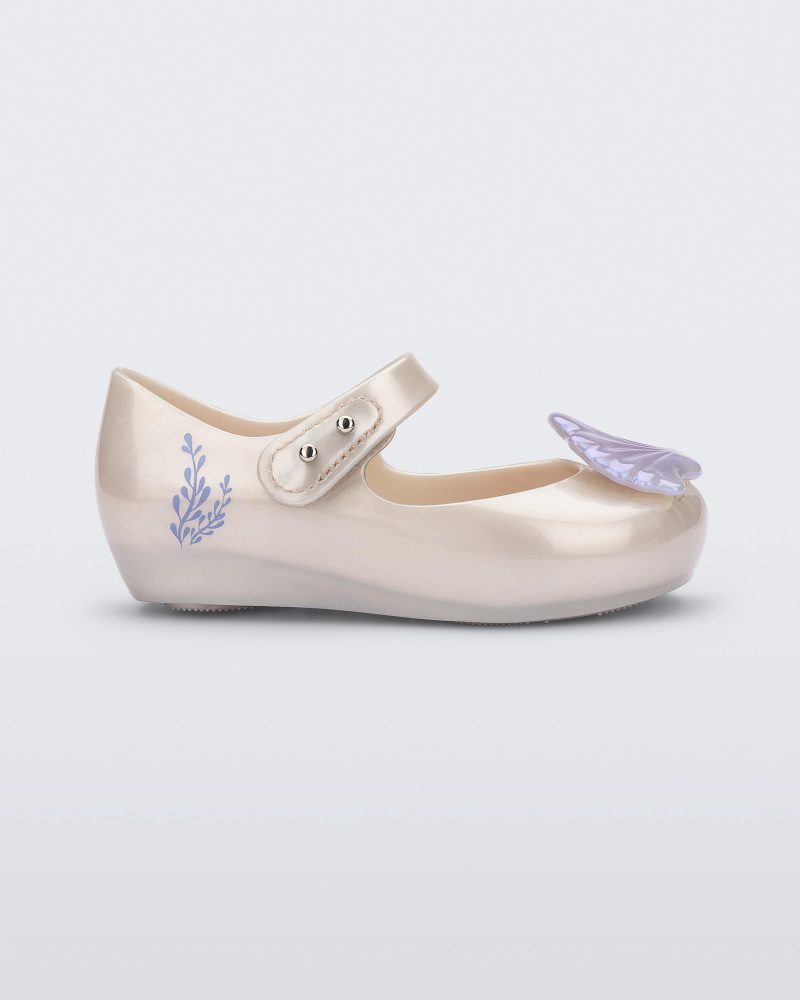 Side view of a pearly white Mini Melissa Ultragirl + Disney Little Mermaid flat with a pearly blue shell on top