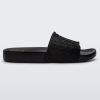 Side view of a black Melissa Slide with the Marc Jacobs logo across the front strap.