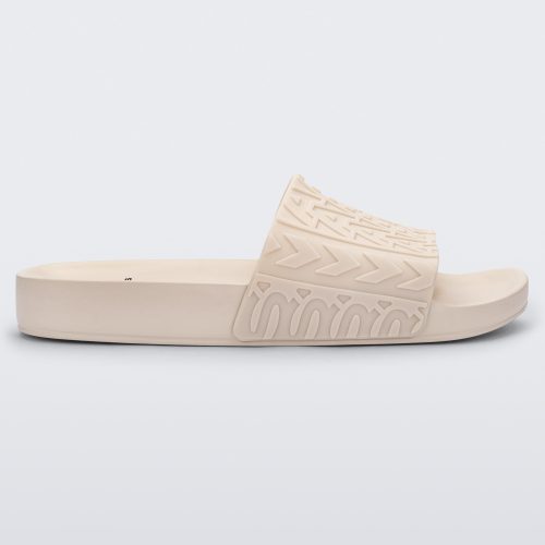 Side view of a beige Melissa Slide with the Marc Jacob's logo across the front strap.