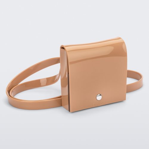 An angled front view of a beige Melissa Like It purse with a silver button and a Melissa logo on the front.