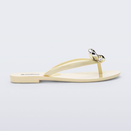 Side view of a beige Harmonic Eclipse flip flop with bow.