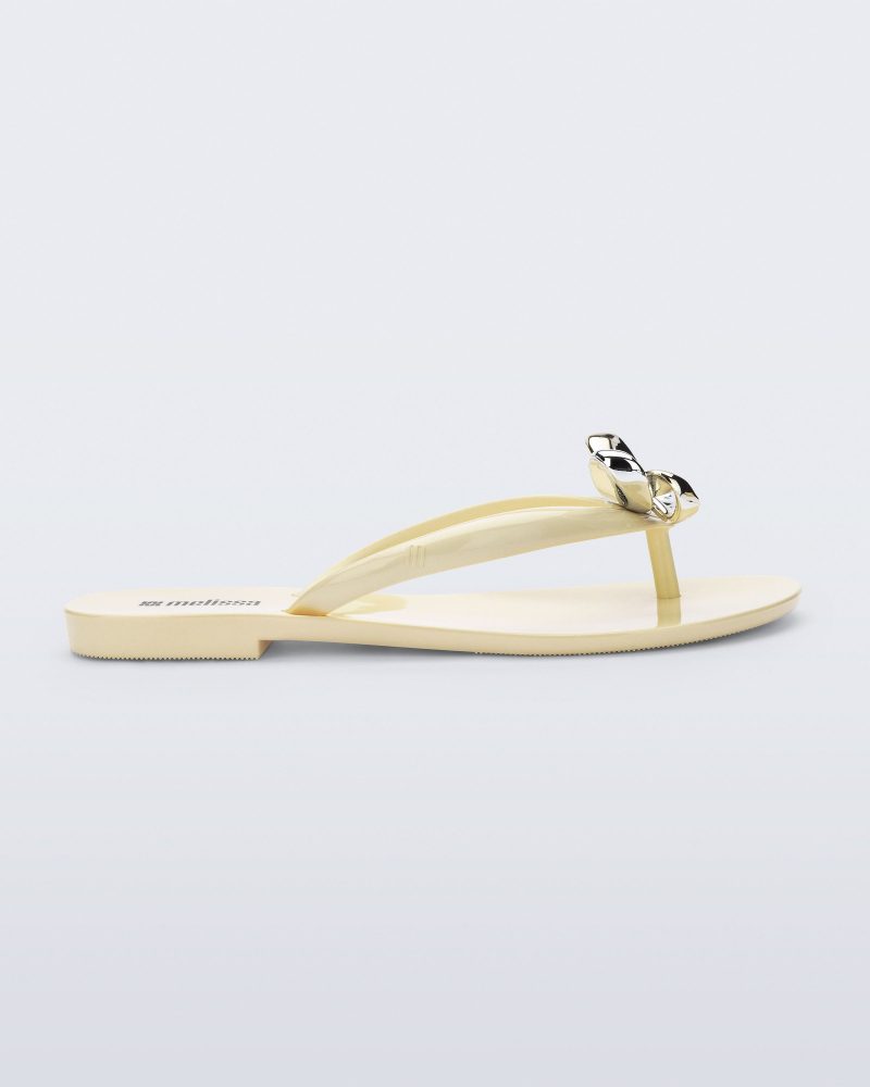 Side view of a beige Harmonic Eclipse flip flop with bow.