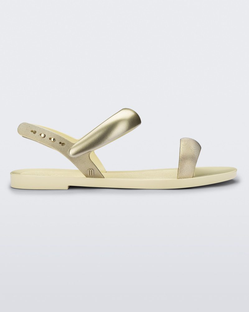 Side view of a beige Eclipse Sandal with gold straps.