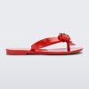 Side view of a red Mini Melissa Harmonic Heart flip flop with a red bow and gold heart detail on the straps