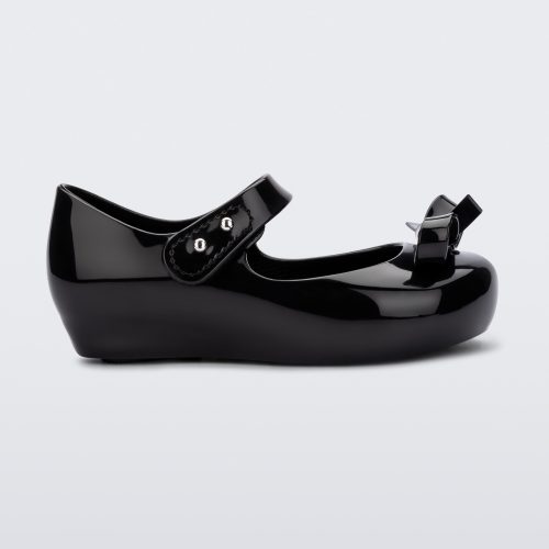 Side view of a black Mini Melissa Ultragirl Bow flat with a black base, top strap and black bow detail on the top.