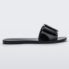 An outter side view of a black Melissa Babe slide with a buckle like bow detail on the front strap.