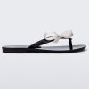 Side view of a black/white Melissa Harmonic Sweet flip flop with a black sole, straps and white bow on top.