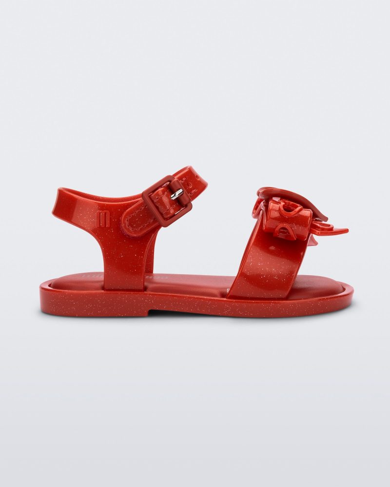 Side view of a glitter red Mini Melissa Mar Sandal Heart sandal with a glitter red heart bow detail on the front strap and an ankle strap