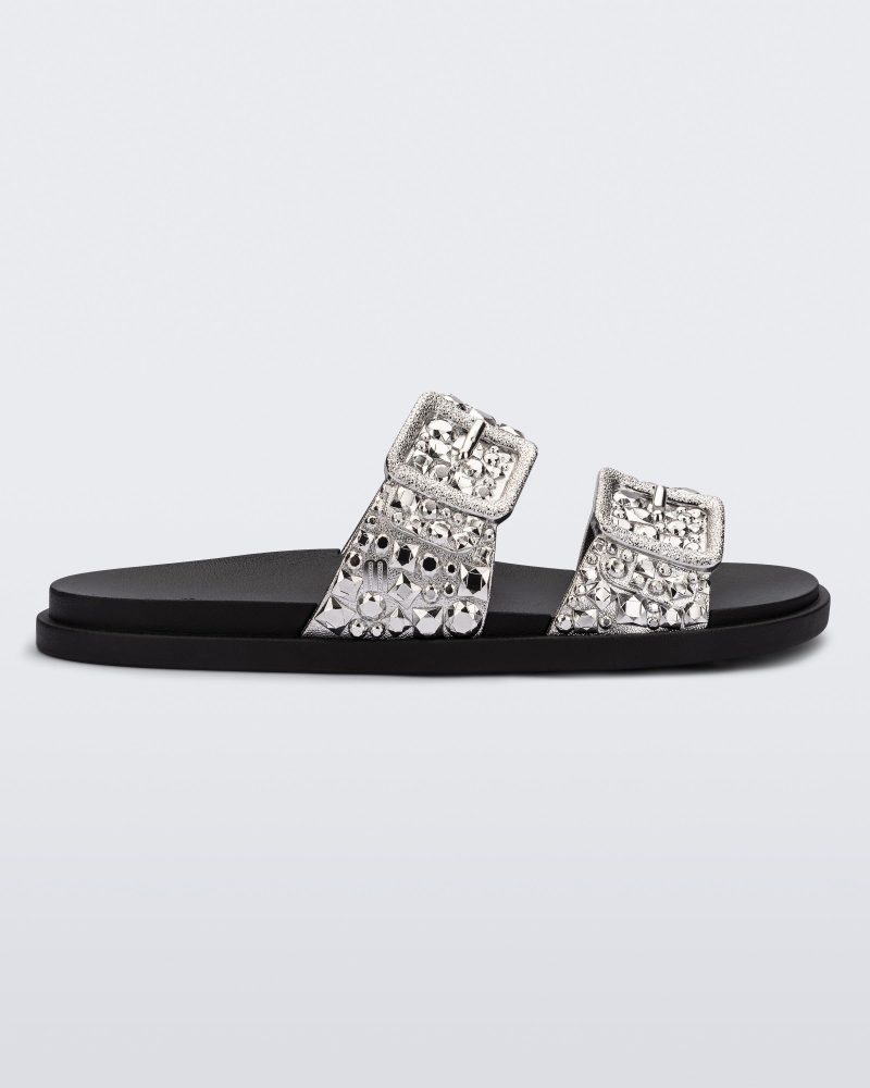 Side view of a black Lust Slide with silver metallic buckle straps