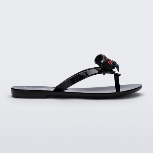 Side view of a black Harmonic M Lover kids flip flop with rainbow Melissa logo on bow