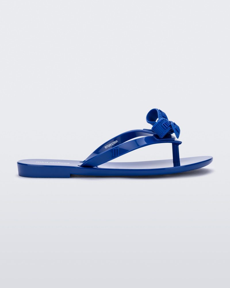 Side view of a blue Harmonic M Lover kids flip flop with Melissa logo on bow